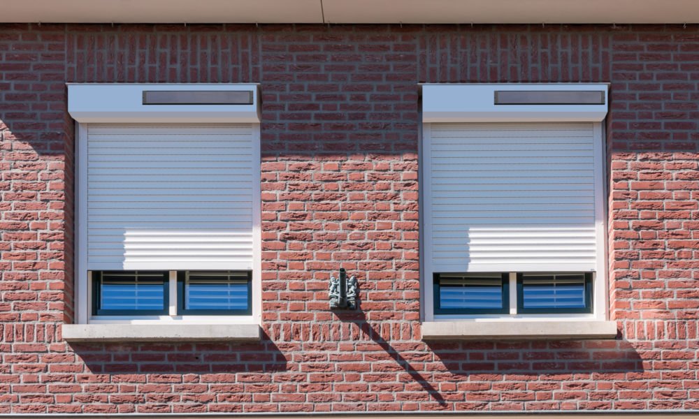 Witte rolluiken op bakstenen gevel
